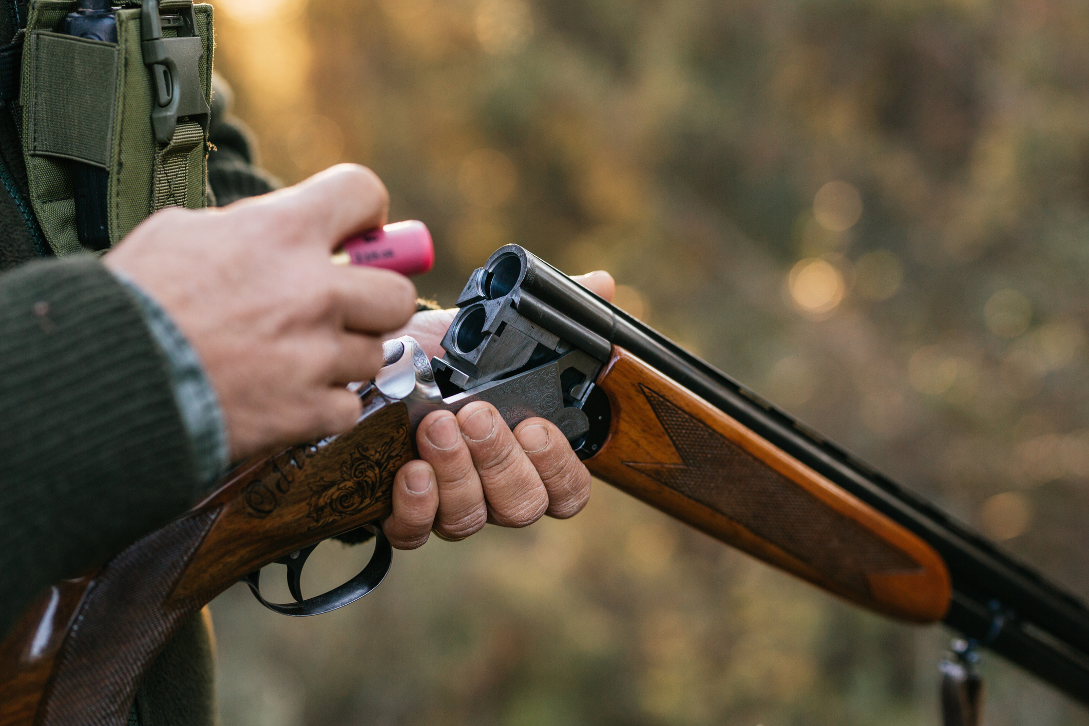 Hände laden Schrotpatrone in aufgeklapptes Jagdgewehr