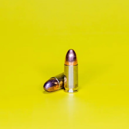 Zwei Patronen stehen und liegen auf gelbem Hintergrund.