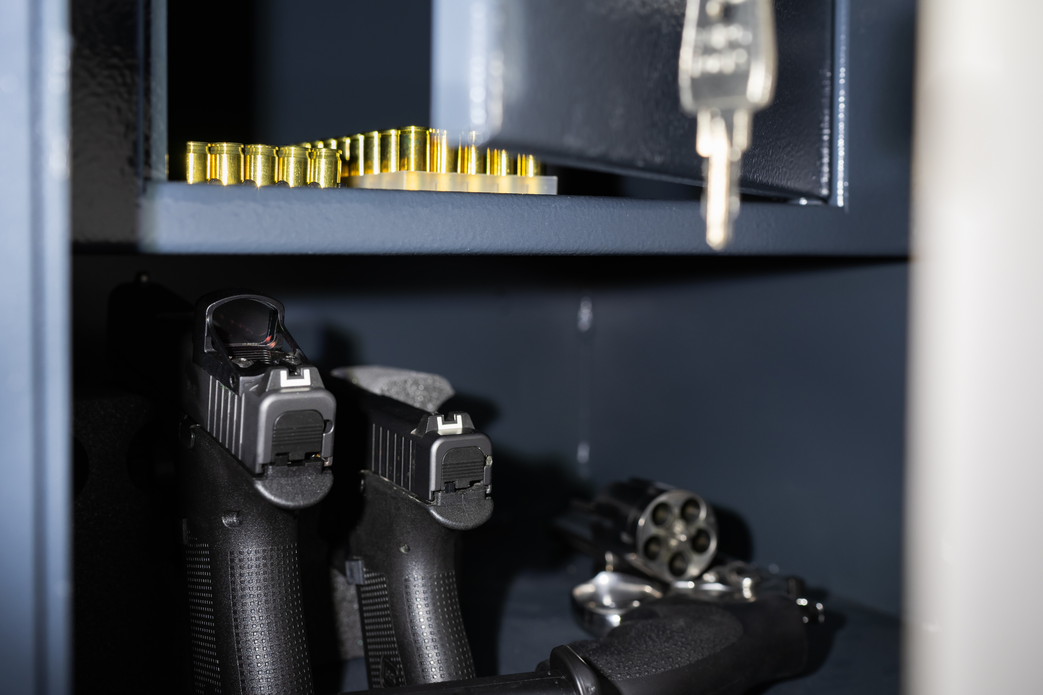 Zwei Pistolen, ein Revolver und Munition in einem geöffneten Waffenschrank.