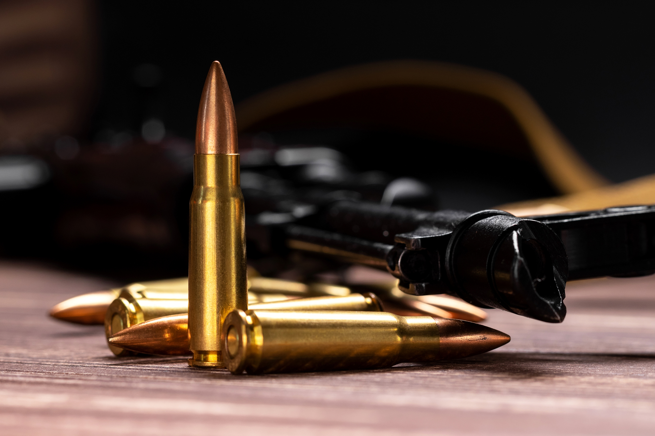 Patronenmunition vor einem Gewehr auf einer Holzoberfläche.