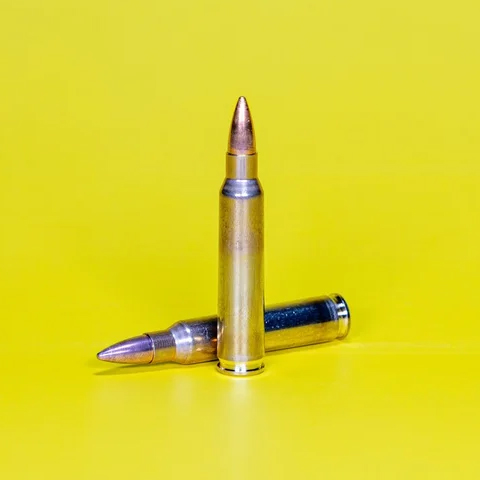 Zwei Patronen stehen & liegen auf gelbem Hintergrund.