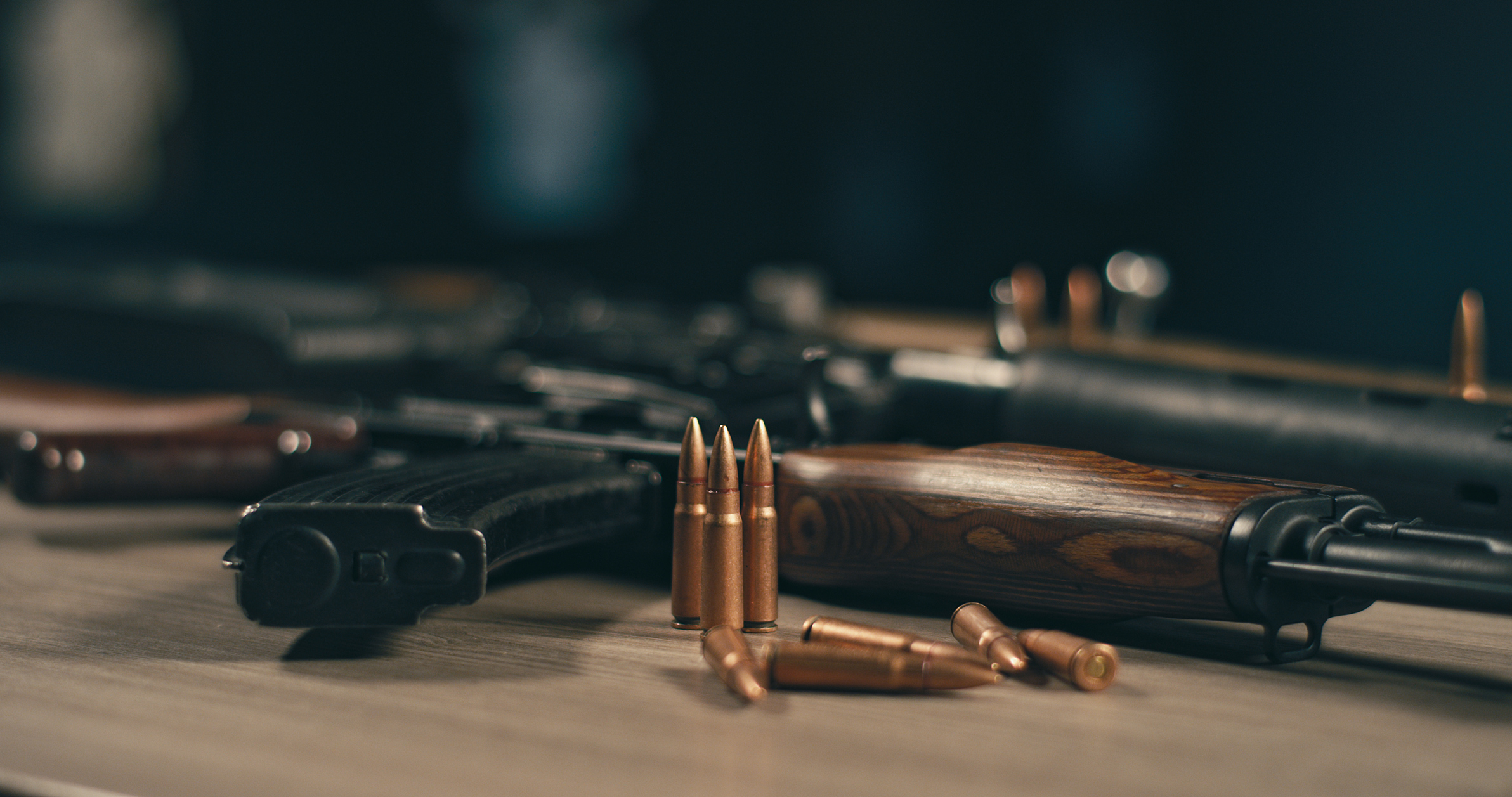 Gewehre und Patronen auf einem Tisch mit Fokus auf Munition im Vordergrund.