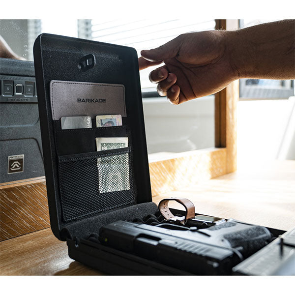 Offene Waffenkiste mit Pistole und Dokumenten, auf einem Holztisch in Innenraum.