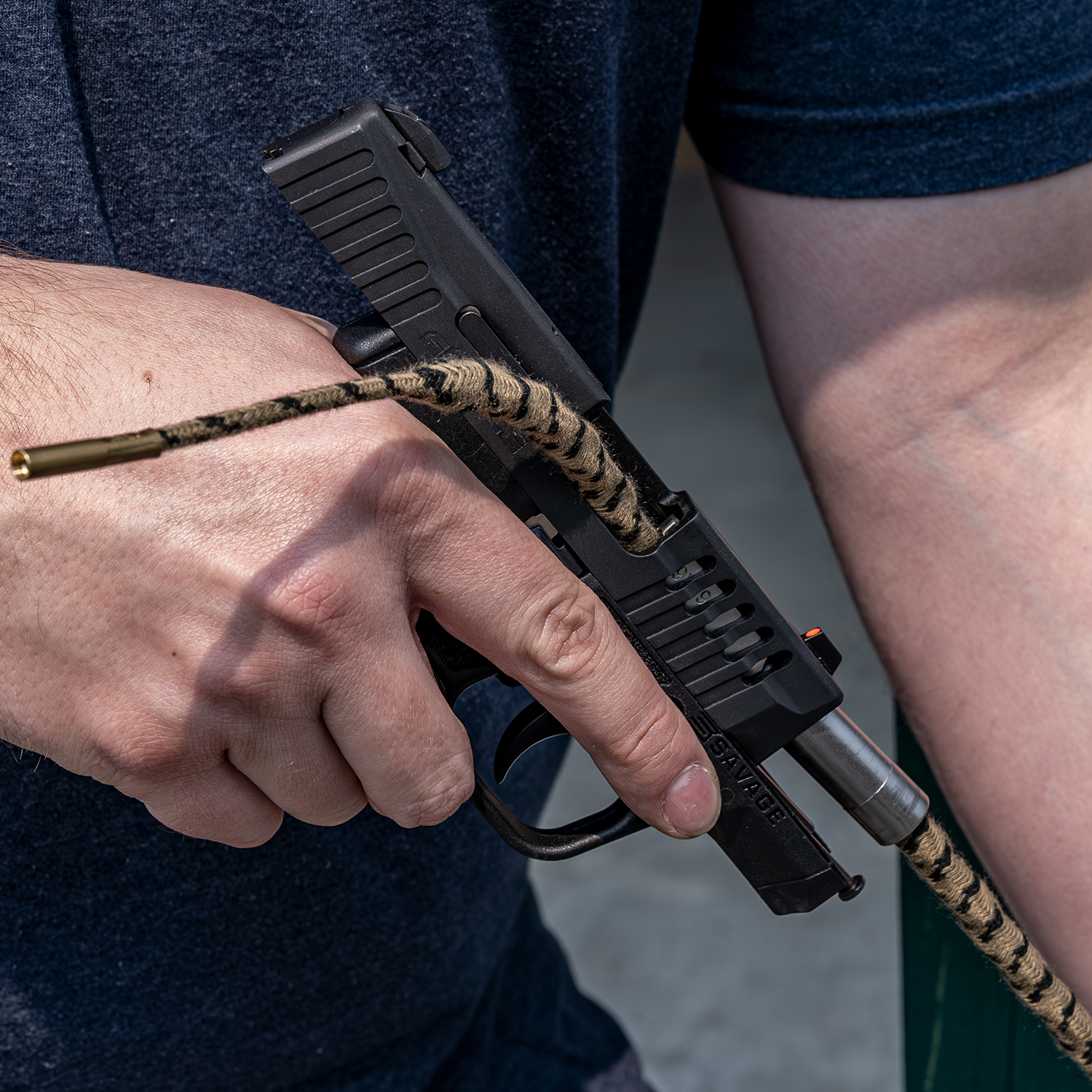 Pistole wird mit Reinigungsschnur gereinigt, gehalten von einer Hand.